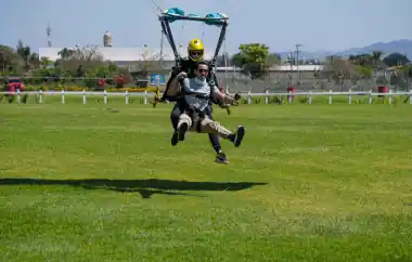Hombre en tándem aterrizando en terreno especial para hacer paracaidismo.  