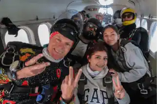 Niño con su familia listos para saltar en paracaídas desde un avión  